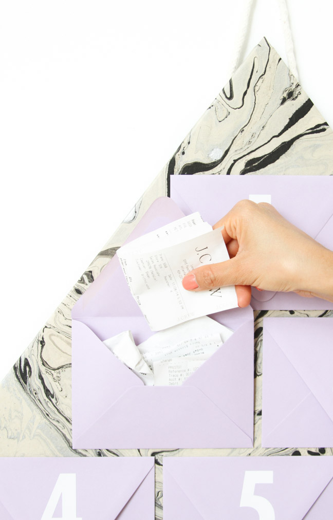 hand adding receipt to envelope marble traingle