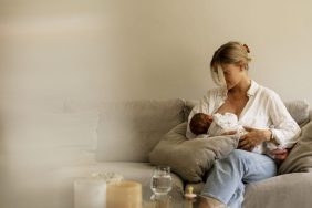 Mother breastfeeding son while sitting on sofa at home