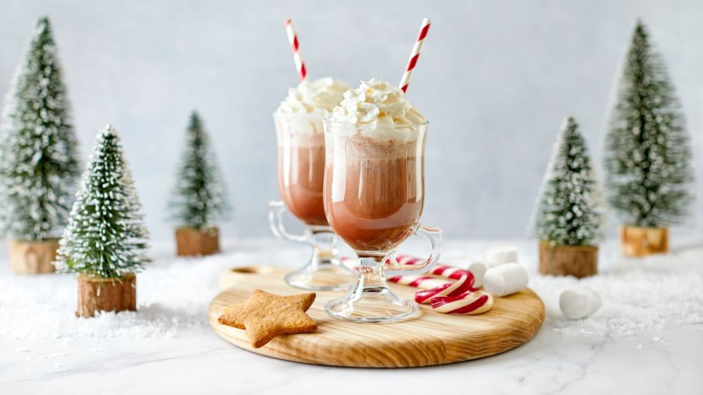 Coffee with whipped cream served with a candy cane, marshmallows, and gingerbread star