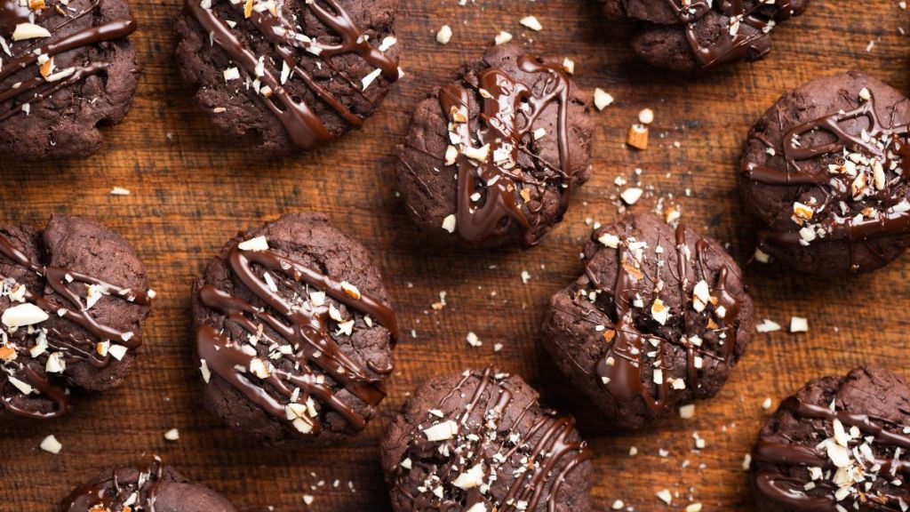 Homemade brownie chocolate cookies decorated with chocolate glaze and crushed almonds, top view