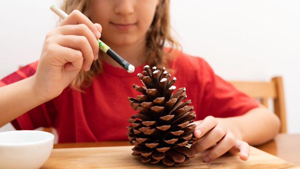 Kid doing DIY craft using pinecone.