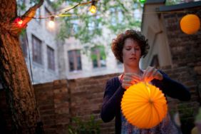 Young woman preparing paper lantern in back yard for garden party