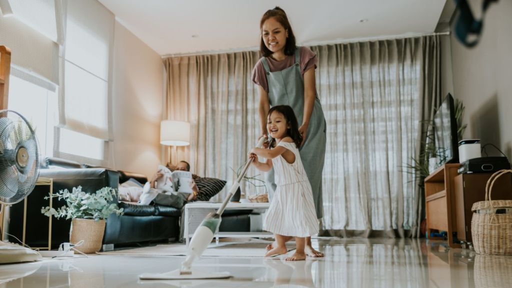 Cute asian toddler girl helping her mom cleaning the floor with mop.