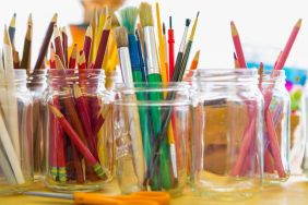 Close up of jars of colored pencils and paintbrushes, a great craft idea for baby food jars