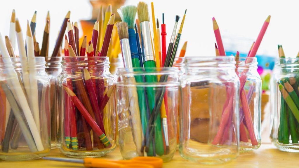 Close up of jars of colored pencils and paintbrushes, a great craft idea for baby food jars