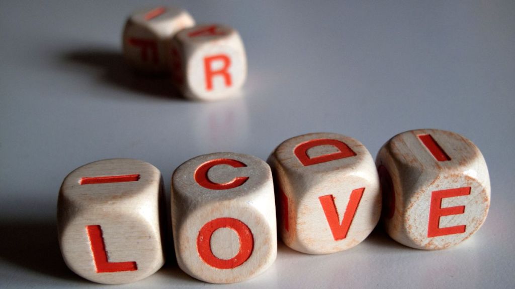 White and orange scrabble dice spelling the word "love."