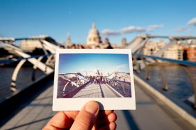 UK, London, St Paul's Cathedral, Millennium Bridge, man holding an instant film photo in front of the scene.