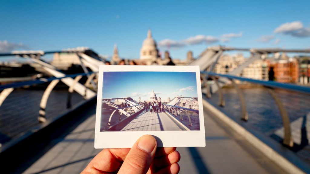 UK, London, St Paul's Cathedral, Millennium Bridge, man holding an instant film photo in front of the scene.