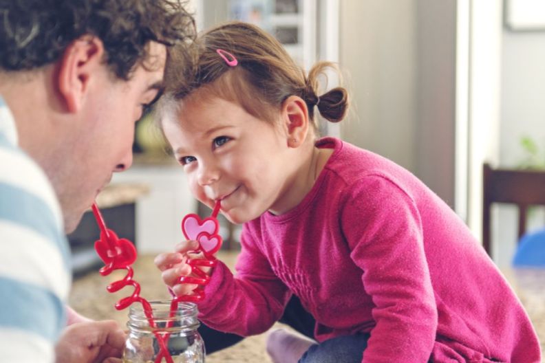 Father and daughter sharing a lemonade using cute Valentine's Day-coded straws.